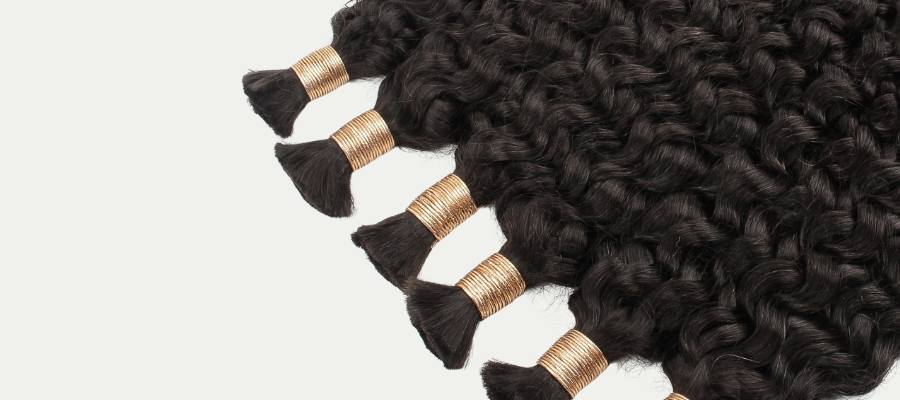 Bundles of curly hair extensions with gold bands on a light gray background
