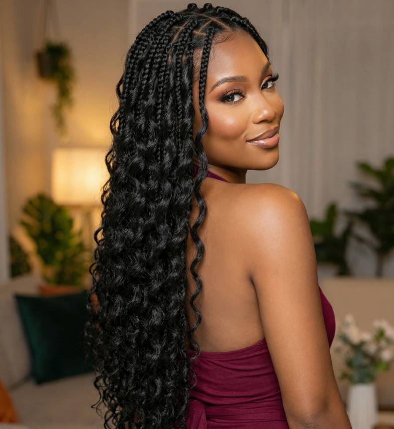 Woman with long, styled feather crocher braids in a home setting