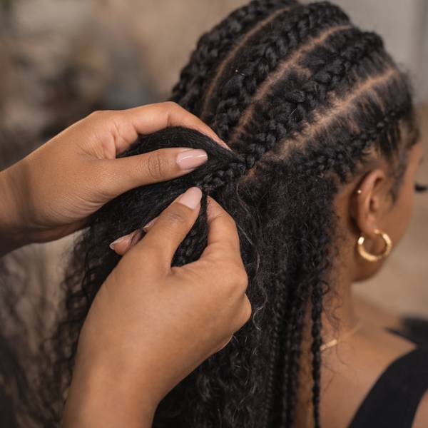 Person braiding another person's hair with a blurred background